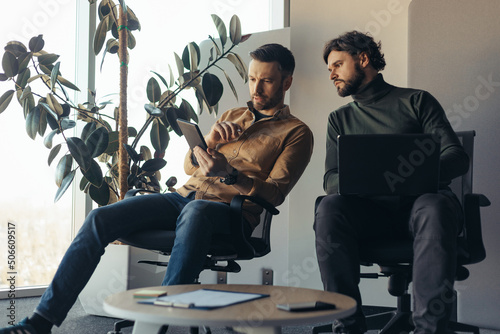 Papier peint Focused male coworkers cooperting, discussing business ideas with laptop compute