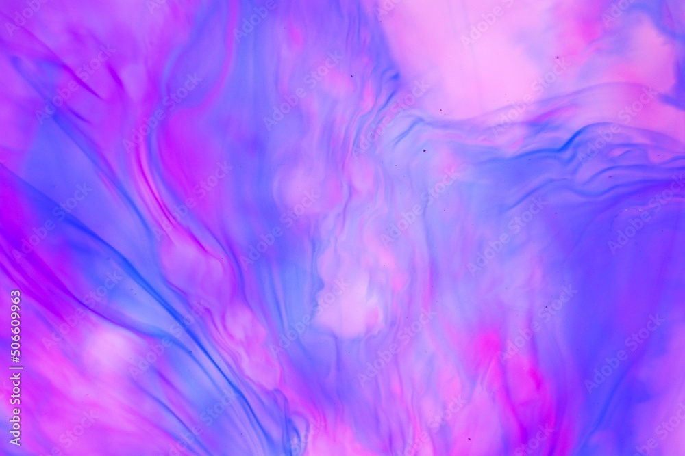 Shallow depth of field shot of swirling pink and blue ink in water - soft flowing abstract and soothing backdrop