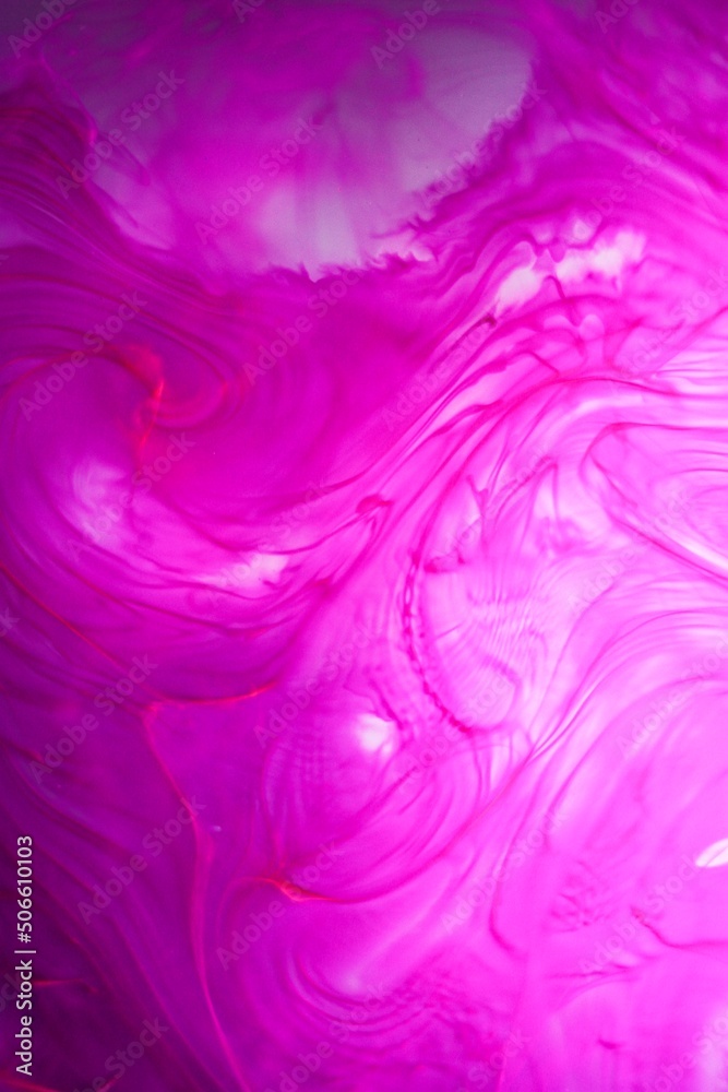 Shallow depth of field shot of swirling pink and blue ink in water - soft flowing abstract and soothing backdrop