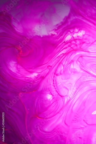 Shallow depth of field shot of swirling pink and blue ink in water - soft flowing abstract and soothing backdrop