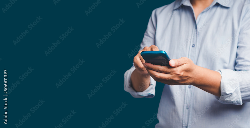 Close-up of hands using a mobile phone while standing over a blue background