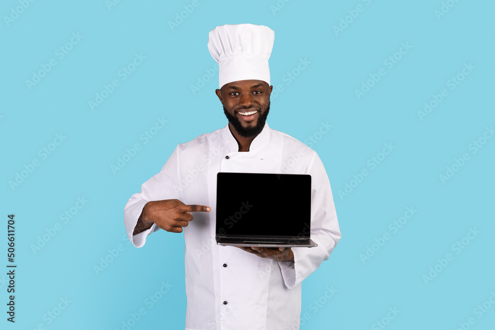 Cooking Website. Smiling Black Chef Pointing At Blank Laptop In His Hand Cooking Website. Smiling Black Chef Pointing At Blank Laptop In His Hand