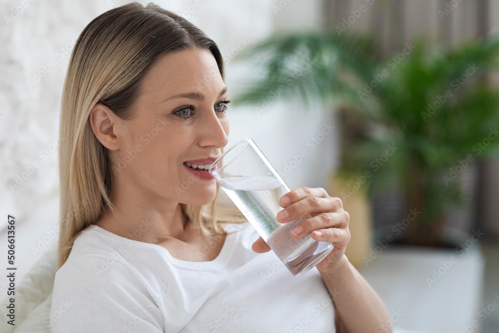 Healthy young lady drinking fresh water after waking up Healthy young lady drinking fresh water after waking up