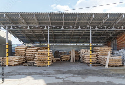Storage and production of wooden stick cuttings for garden tools. Warehouse of household goods under a canopy on pallets. Handle for shovel and household equipment