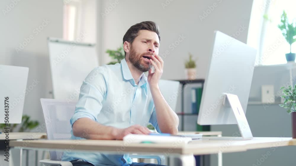 Bored sleepy office worker sitting at work workplace at computer desk leaning on hand yawning. Tired man. Exhausted Businessman employee. Portrait Depressed, unhappy, workless male manager. indoor Bored sleepy office worker sitting at work workplace at computer desk leaning on hand yawning. Tired man. Exhausted Businessman employee. Portrait Depressed, unhappy, workless male manager. indoor