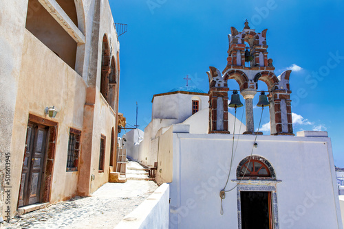 Fototapeta Naklejka Na Ścianę i Meble -  The bell tower on Santorini streets under blue sky during sunny day.