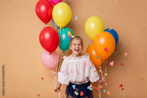 Happy Birthday party. Child girl with balloons on beige background