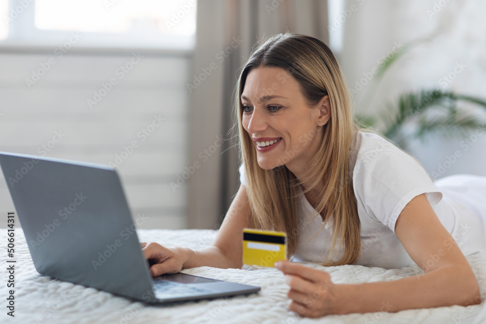 Happy young woman with laptop and credit card at bedroom Happy young woman with laptop and credit card at bedroom