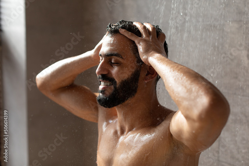 Handsome happy young Arabic male model taking hot shower