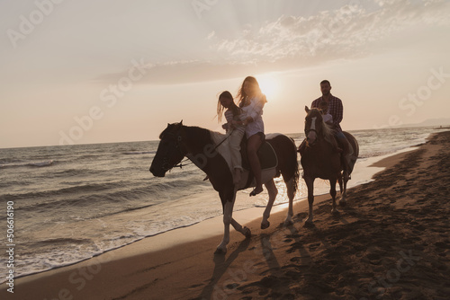 Fototapeta Naklejka Na Ścianę i Meble -  The family spends time with their children while riding horses together on a sandy beach. Selective focus 