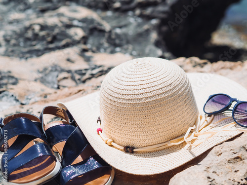 Summer accessories on the beach. Woman sandals, summer hut and sunglasses