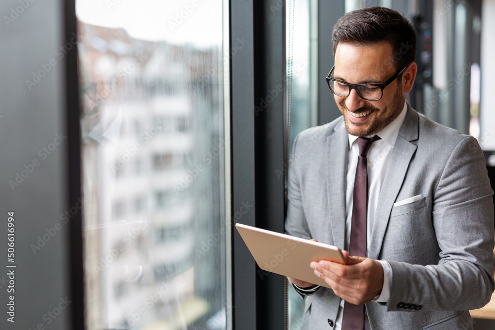 Happy business man manager holding tablet and working in modern office