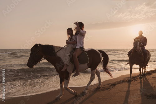 The family spends time with their children while riding horses together on a sandy beach. Selective focus 