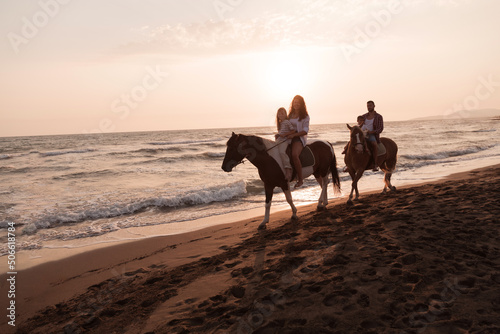 The family spends time with their children while riding horses together on a sandy beach. Selective focus 