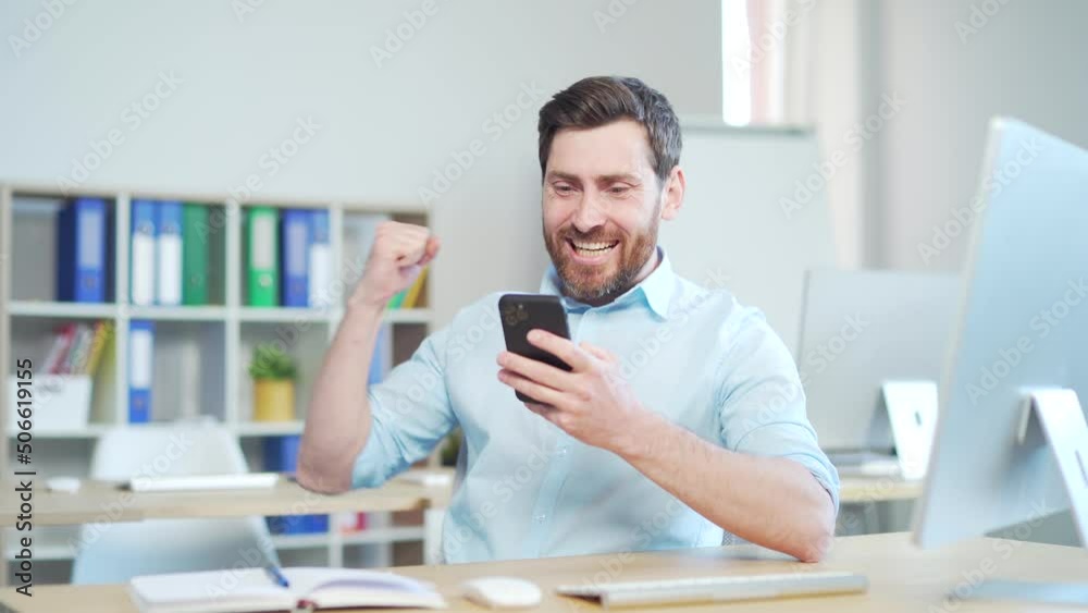 Happy euphoric bearded business man celebrate mobile win, excited overjoyed lucky executive winner receive good news in message use smartphone rejoice bet financial success victory Sitting in office Happy euphoric bearded business man celebrate mobile win, excited overjoyed lucky executive winner receive good news in message use smartphone rejoice bet financial success victory Sitting in office