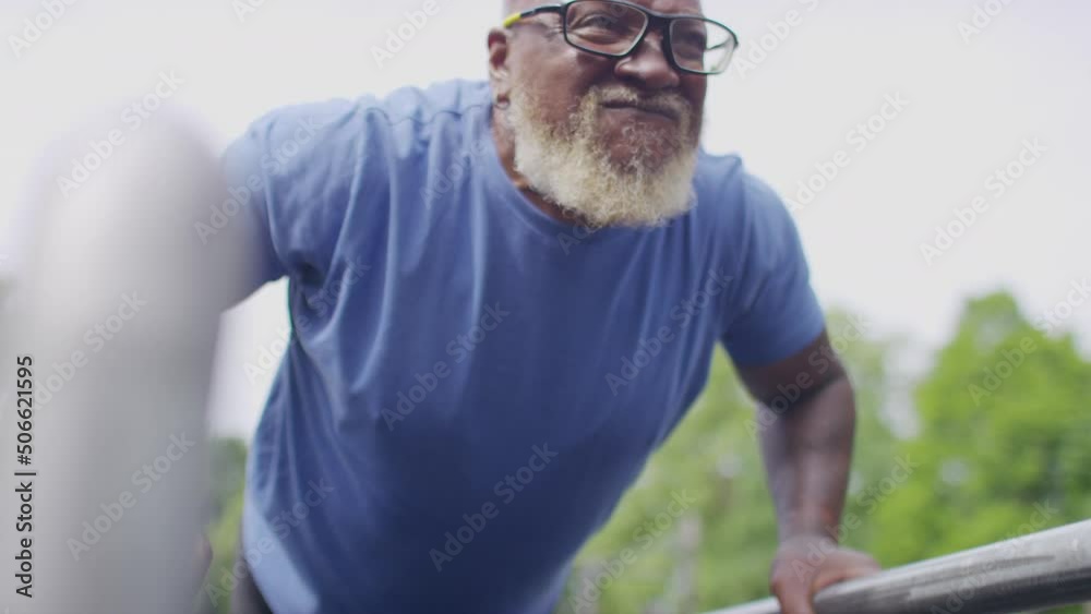 Active senior man working out doing push ups on bars in an outdoor gym location