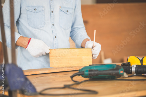 Carpenter working with equipment on wooden table in wood workshop, man doing woodwork in carpentry shop