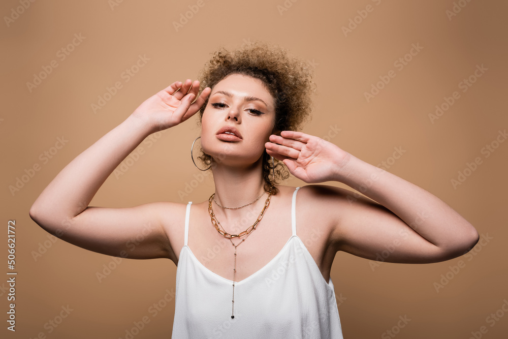 Obraz premium Pretty woman in white top looking at camera isolated on beige.