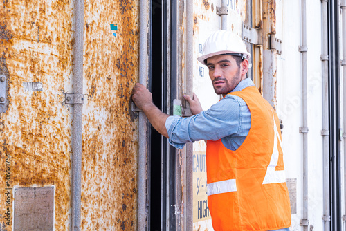 Attractive engineer construction foreman wears uniform is working in the construction container yard on the background. Industrial container yard for import and export for business logistic concept.