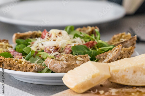 Blocks of parmesan cheese and a salad with salami and bread.