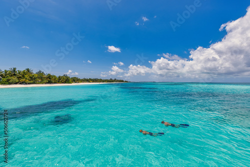Caucasian couple of tourists snorkel in crystal turquoise water near Maldives Island. Perfect weather conditions at luxury resort beach scene, calm sea water, couple exotic water, underwater wildlife 