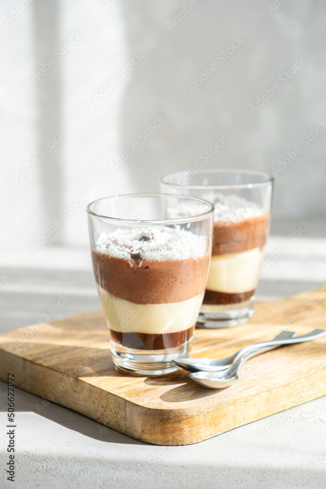 Unusually delicious three-layer chocolate-vanilla and creme brulee mousse dessert, decorated with coconut flakes. Snack in cafes and at home, brunch Unusually delicious three-layer chocolate-vanilla and creme brulee mousse dessert, decorated with coconut flakes. Snack in cafes and at home, brunch