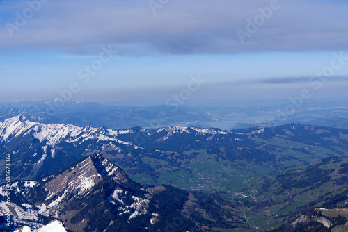 Panoramic landscape with rocks and hills with Lake Zürich in the background seen from Säntis peak at Alpstein Mountains on a sunny spring day. Photo taken April 19th, 2022, Säntis, Switzerland.