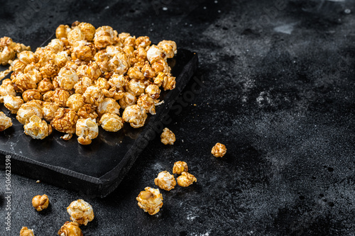 Homemade Crunchy Caramel Popcorn on marble board. Black background. Top view. Copy space