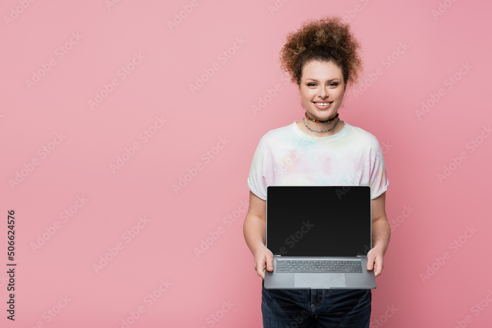Cheerful woman holding laptop with blank screen isolated on pink. Cheerful woman holding laptop with blank screen isolated on pink.