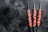 Raw mince lamb meat shish kebab on butcher table. Black background. Top view. Copy space