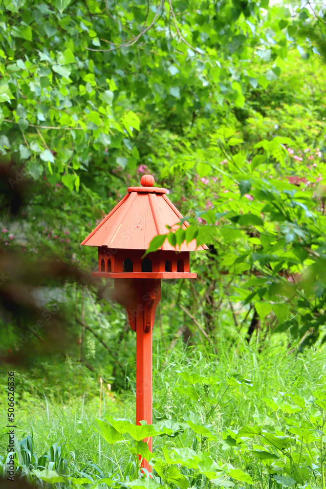 Cute red birdhouse in the beautiful park. Beautiful spring or summer day. Selective focus.