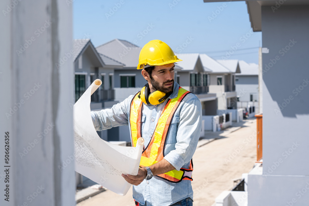 Architect in yellow helmets reviewing blueprints at a construction site. Architect in yellow helmets reviewing blueprints at a construction site.