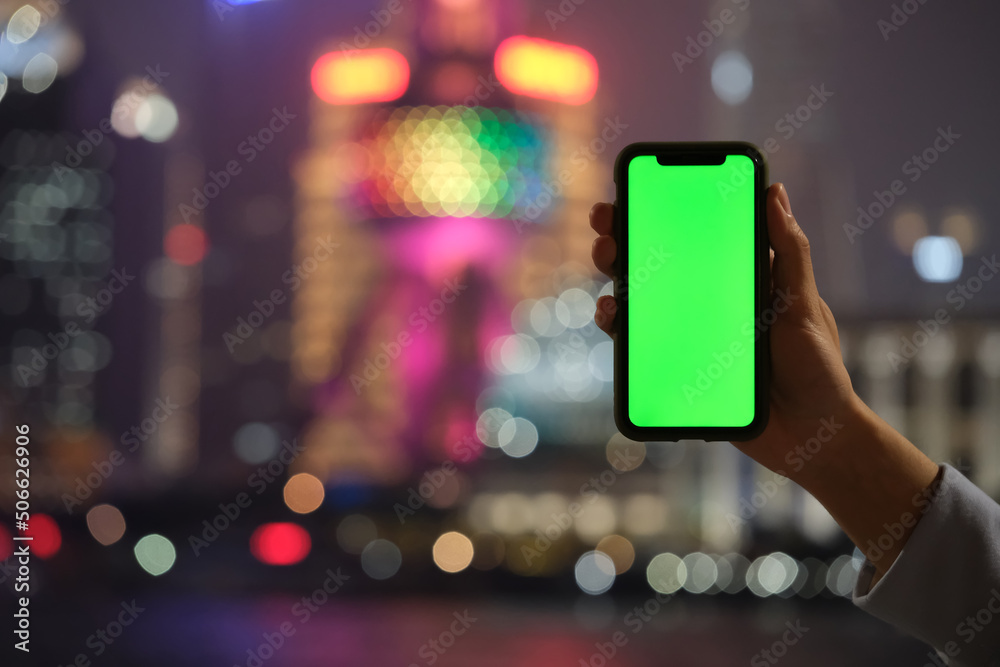 hand showing green screen phone with blur colorful Shanghai city bokeh background hand showing green screen phone with blur colorful Shanghai city bokeh background