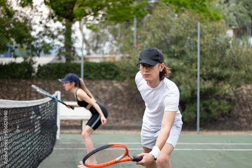 Side view of man and woman tennis couple concentrating on playing a match near the net trying to hit the ball. © NOWRA photography