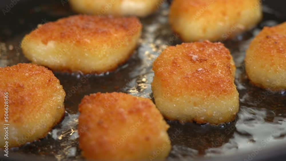 Close up of fried chicken nuggets in hot oil in frying pan. Nuggets fry with crispy crust. Snack, fast food Close up of fried chicken nuggets in hot oil in frying pan. Nuggets fry with crispy crust. Snack, fast food