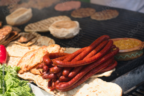 Traditional serbian street food (roštilj) - pljeskavica, ćevapi, grilled chicken breast, bbq chicken wings and homemade sausages served with fresh bakery (lepinja) photo