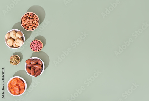 Mix of dried fruits and nuts in bowls - symbols of judaic holiday Tu Bishvat. green background, copy space.
