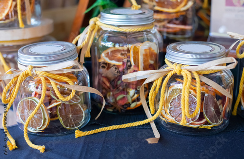 Dried candied orange slices lie in glass jars with yellow laces on the market, close-up