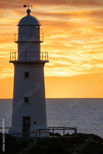 Lighthouse silhouette against the backdrop of the ocean and sunset, blue evening sky and clouds, landscape
