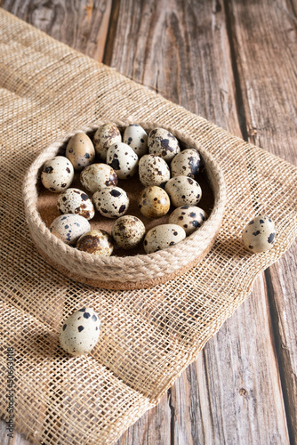 Fresh quail eggs in a basket on a horn and wooden background