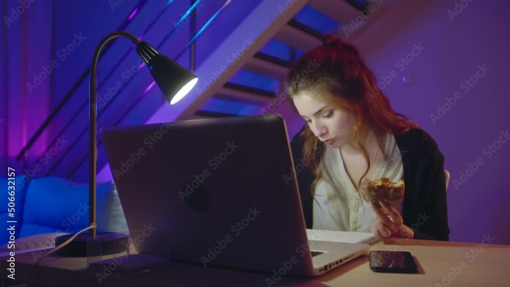 Beautiful Girl Student Makes Sketches In A Sketchbook Using Laptop At Home Office In The Evening. Busy Hungry Freelancer Girl Eats a Donut Unhealthy Food While Doing Her Work Tasks Beautiful Girl Student Makes Sketches In A Sketchbook Using Laptop At Home Office In The Evening. Busy Hungry Freelancer Girl Eats a Donut Unhealthy Food While Doing Her Work Tasks