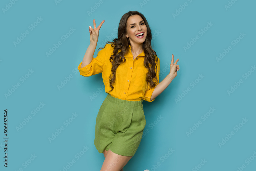 Happy young woman in linen shirt and shorts is showing peace hand sign. Happy young woman in linen shirt and shorts is showing peace hand sign.