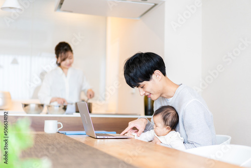 赤ちゃんと一緒にパソコンを使うパパ