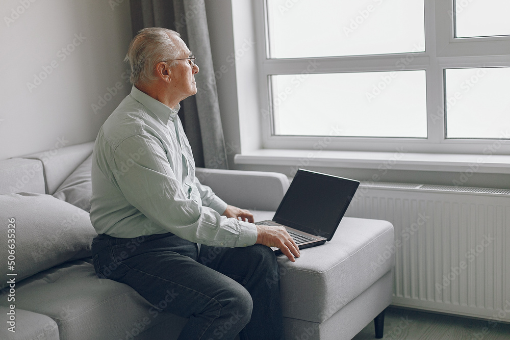 Elegant old man sitting at home and using a laptop Elegant old man sitting at home and using a laptop