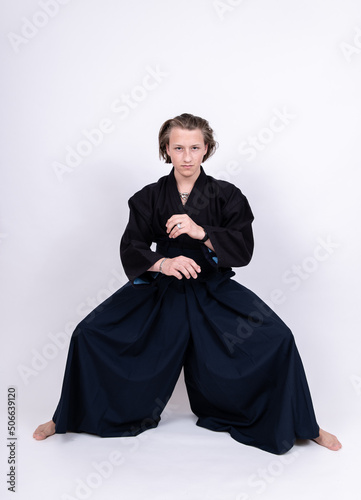 Obraz na płótnie junger mann in traditionellem Kendo Gewand mit gebeugten Knien und gekreuzten Armen w salonie