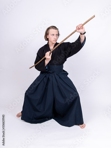 junger mann in traditionellem Kendo Gewand, Stock schräg vor sich