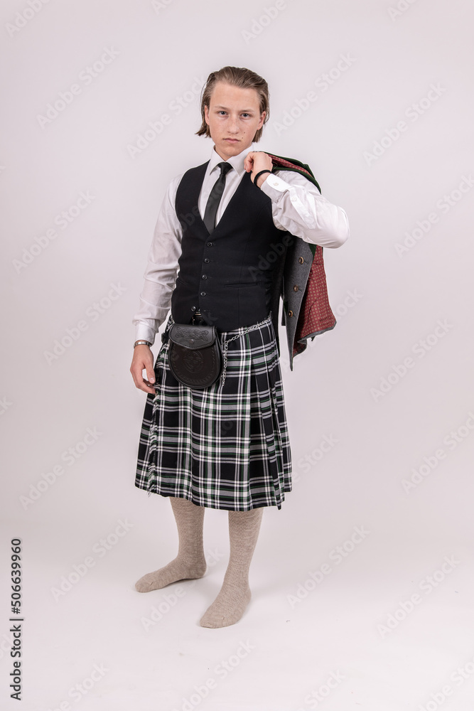 blonder, junger Mann trägt einen Kilt und Trachtenjacke über der Schulter