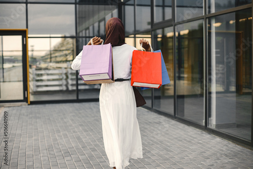 Canvas Print Backside photo of arabic woman wearing hijab standing with shopping bags