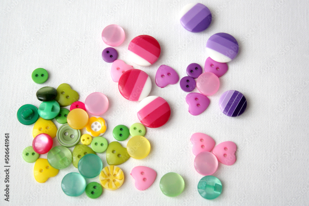 Many multi-colored funny buttons on a white background. Buttons for sewing clothes and needlework. Many multi-colored funny buttons on a white background. Buttons for sewing clothes and needlework.