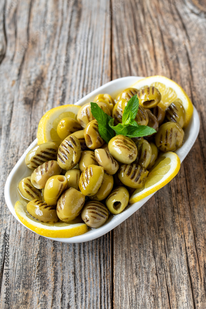 Grilled green olives. natural olive on wood floor background. Healthy food. close up Grilled green olives. natural olive on wood floor background. Healthy food. close up